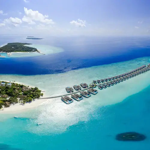 Aerial view of luxurious overwater bungalows surrounded by pristine turquoise waters and sandy beaches.
