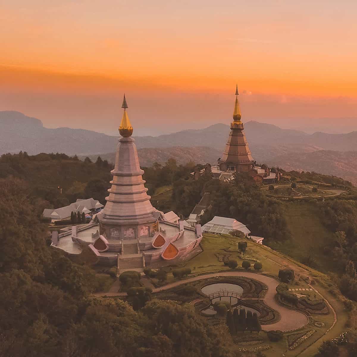 Stunning sunset view of two pagodas on a mountain in Thailand's landscape.