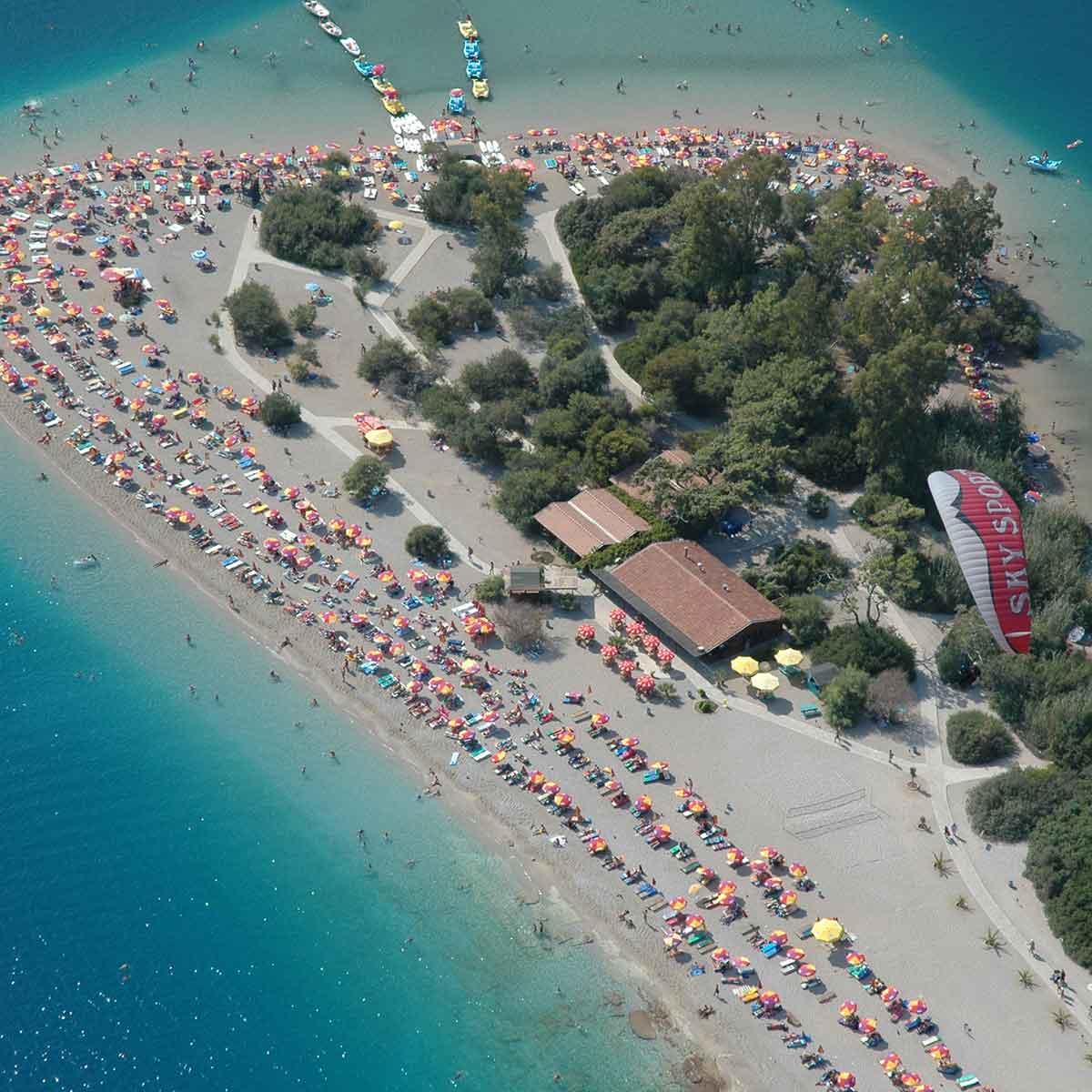 Aerial view of a crowded beach in Fethiye, showcasing umbrellas and sunbathers on a sunny day.