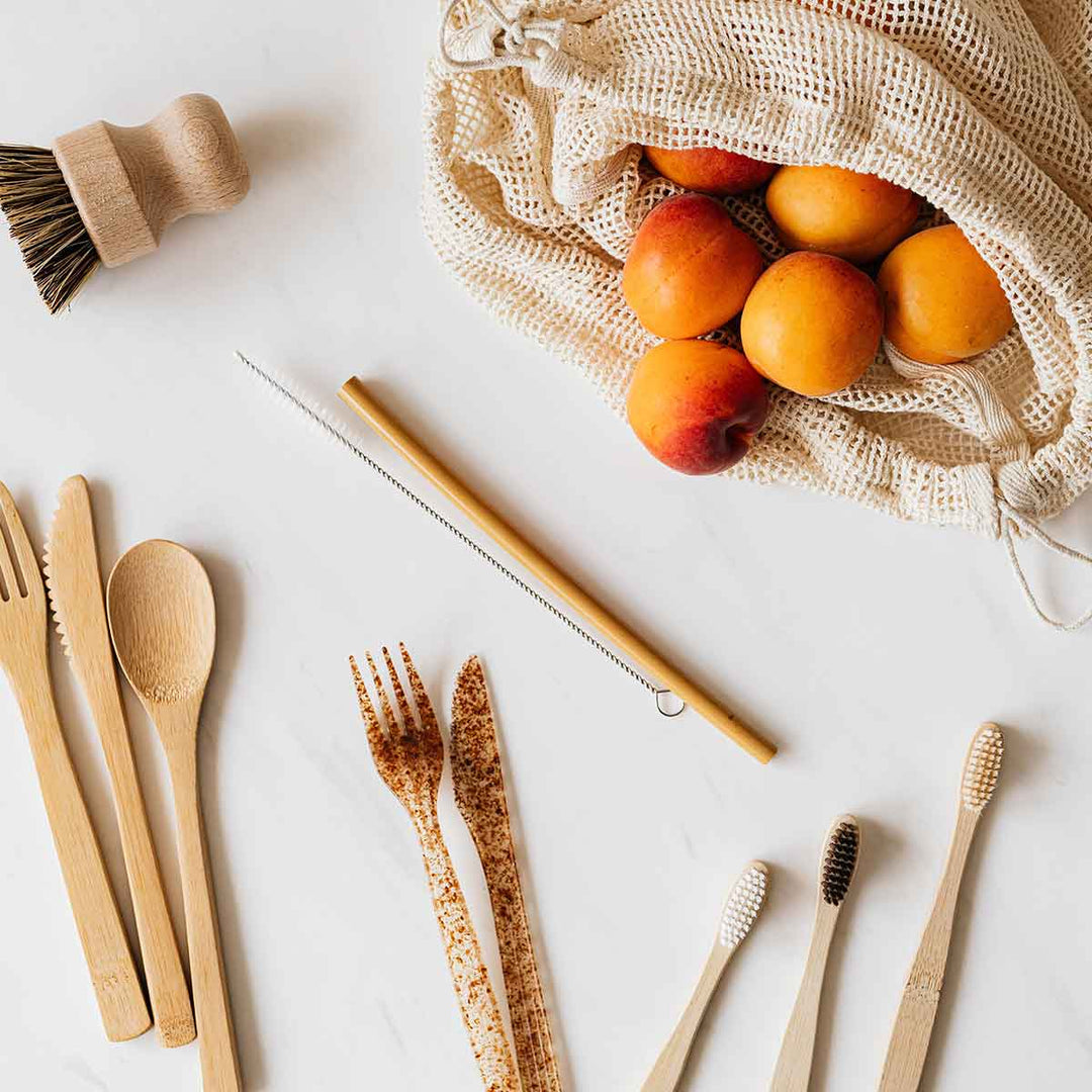 Eco-friendly kitchen utensils and natural fruits in a reusable bag promoting sustainable living.