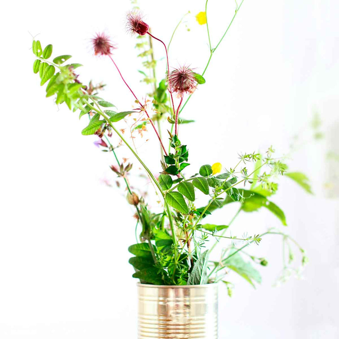 Recycled can holding colorful wildflowers and greenery for home decor.