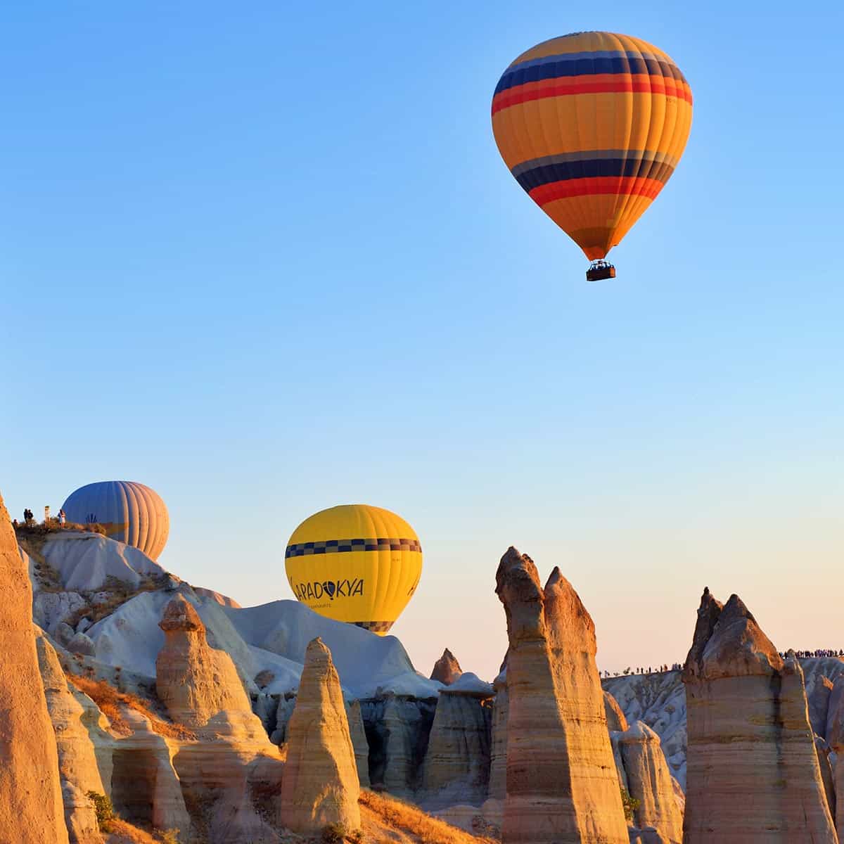 Colorful hot air balloons over Cappadocia's unique fairy chimneys at sunrise.