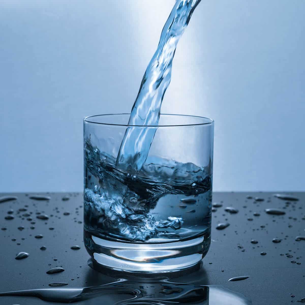 Fresh water being poured into a clear glass, showcasing the importance of clean drinking water.