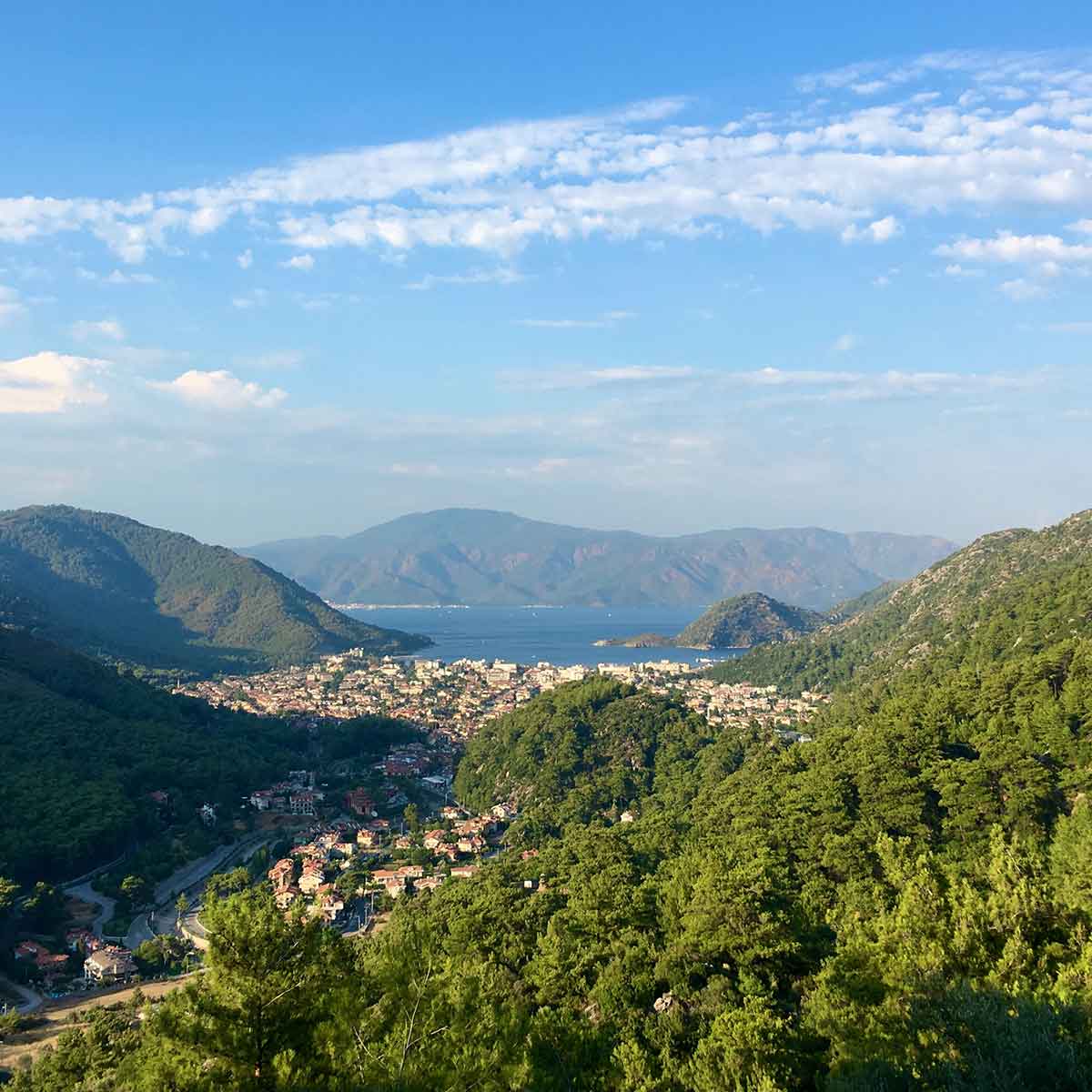 Panoramic view of Marmaris highlighting lush green mountains and a tranquil bay under a blue sky.