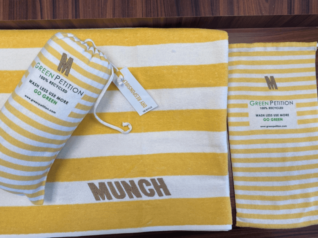 Eco-friendly striped towels featuring 'MUNCH' branding and a Green Petition tag promoting recycling.