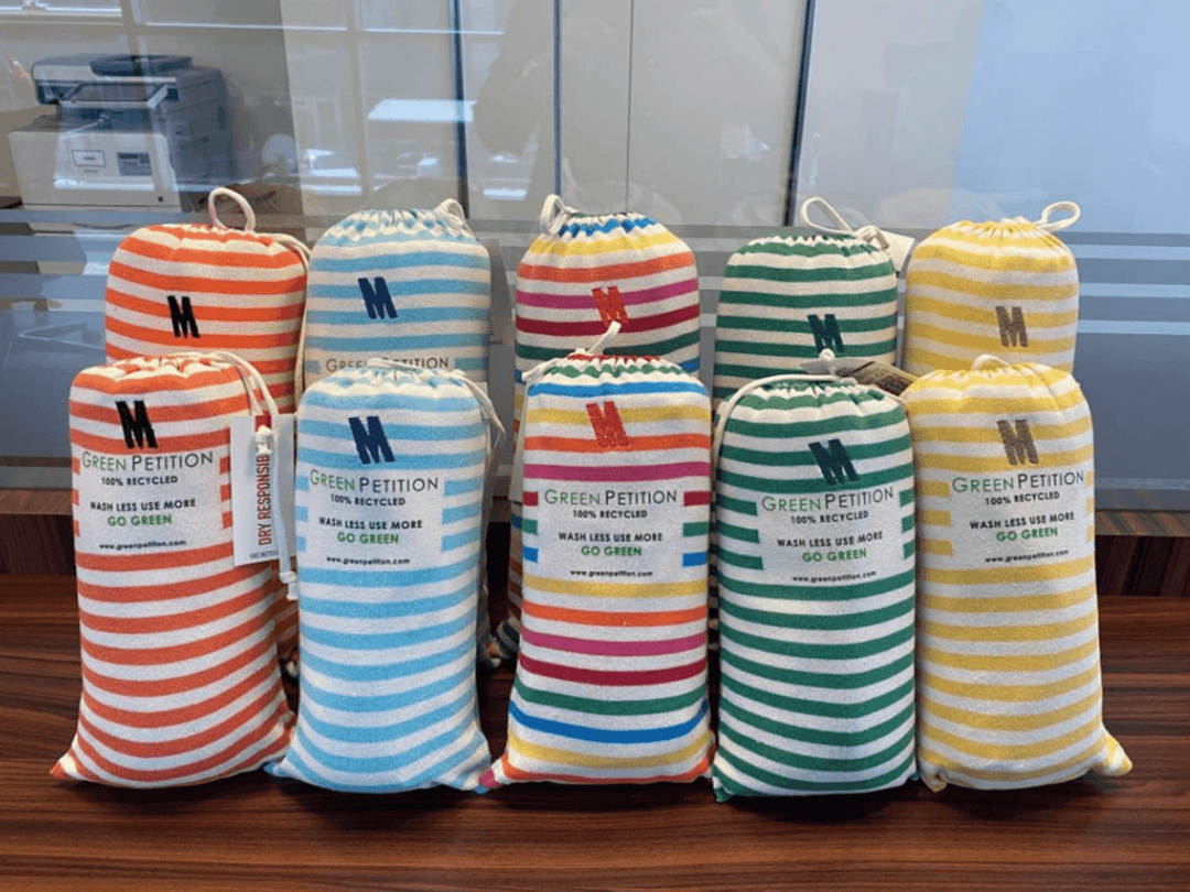 Colorful eco-friendly bags from Green Petition promoting sustainability and going green in a modern office setting.