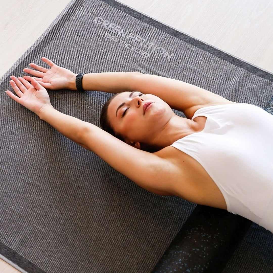 Woman relaxing on a yoga mat labeled 'Green Petition' showcasing eco-friendly materials and design.