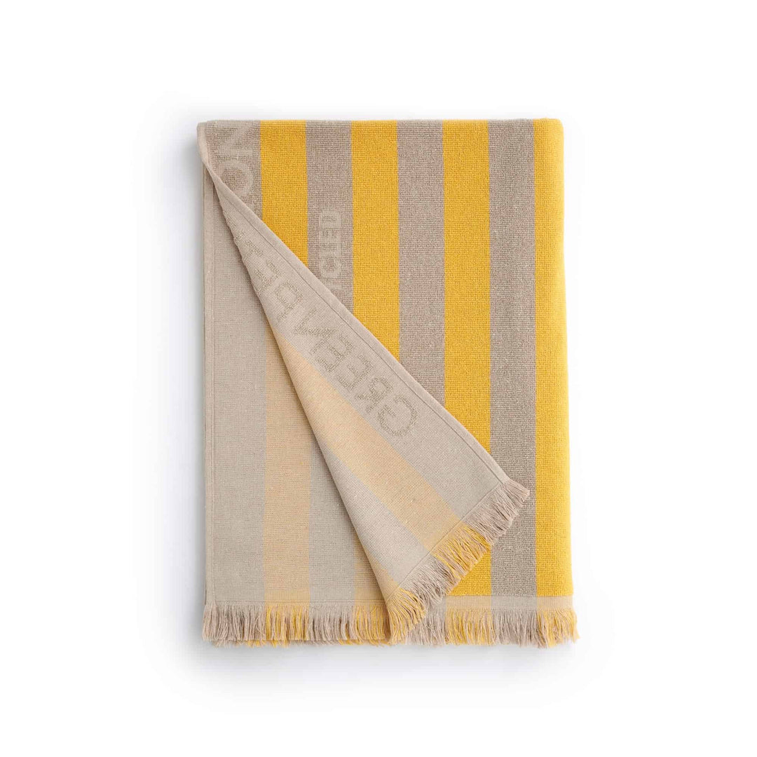 Maris Amber Beach Towel with striped design in yellow and gray, perfect for sustainable comfort and stylish beach outings.