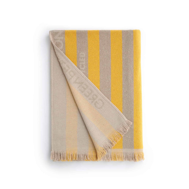 Maris Amber Beach Towel with striped design in yellow and gray, perfect for sustainable comfort and stylish beach outings.