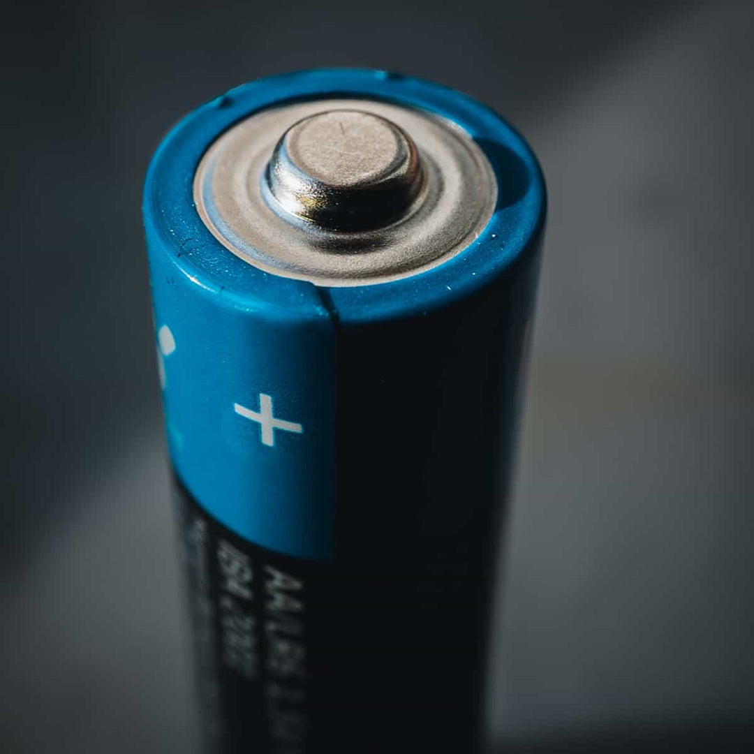 Close-up view of a used AA battery highlighting its positive terminal for recycling awareness.