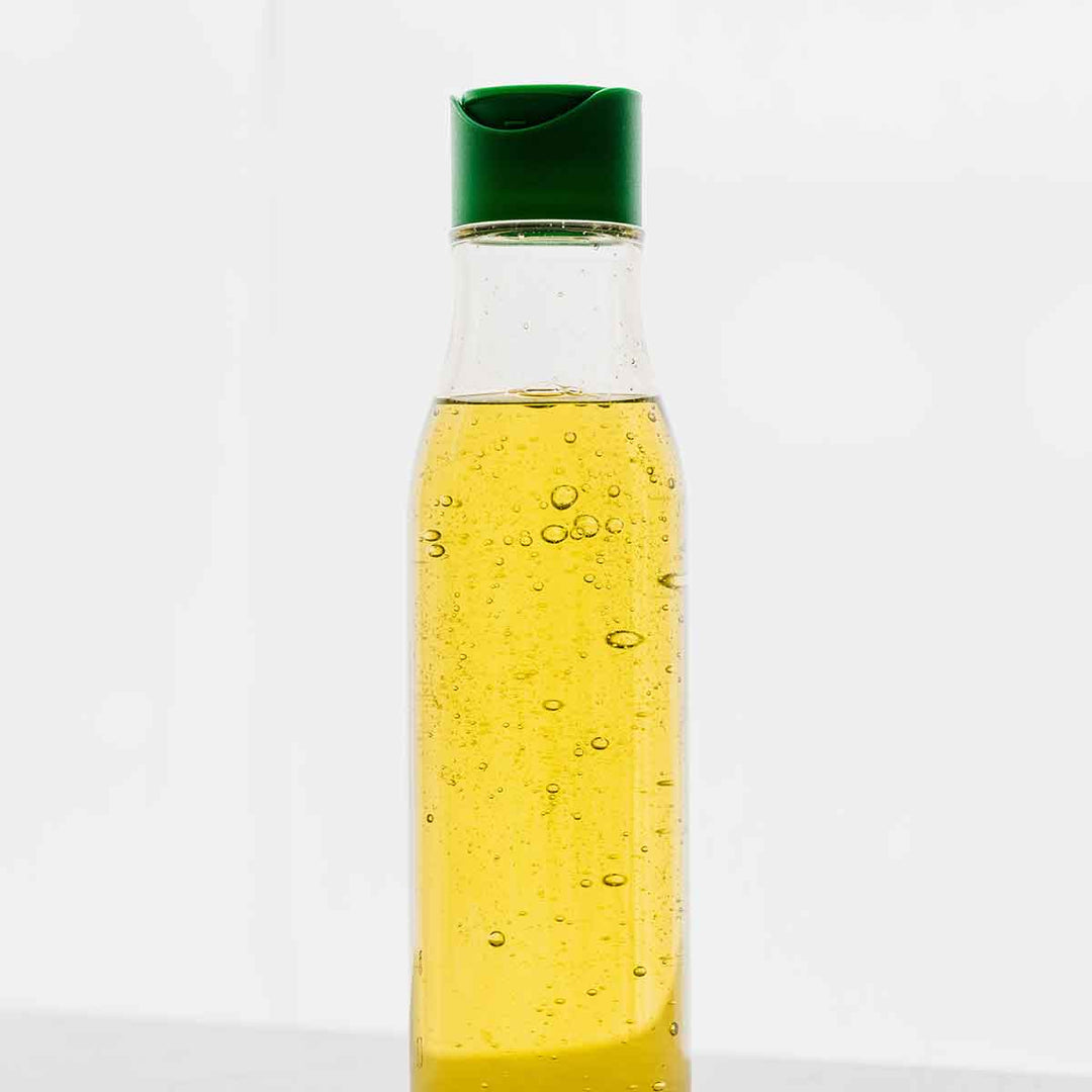 Bottle filled with yellow vegetable oil, showcasing clarity and bubbles in the liquid.