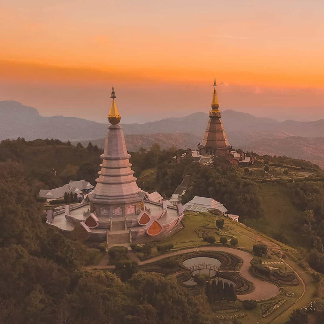 Stunning sunset view of two pagodas on a mountain in Thailand's landscape.