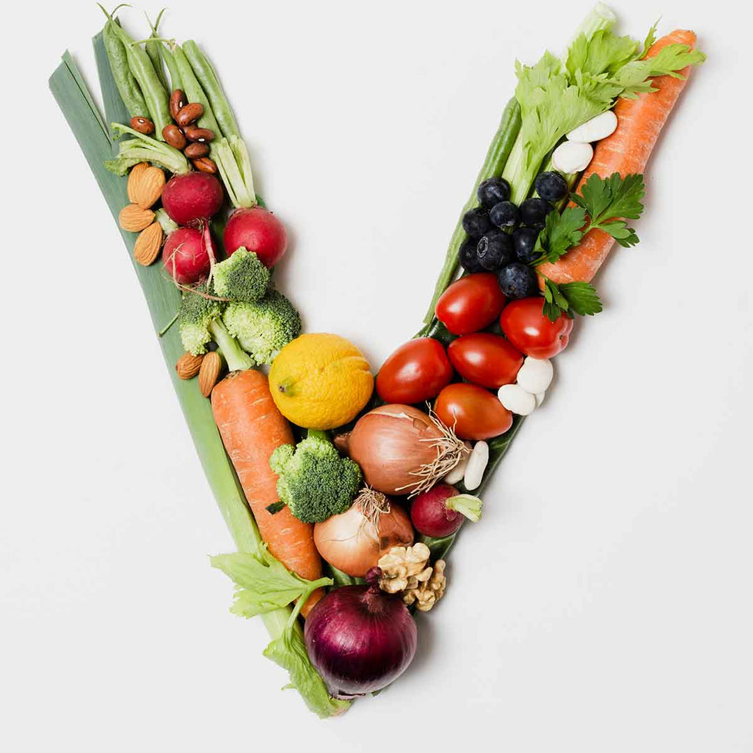 V-shaped arrangement of various fresh vegetables and fruits representing a vegan lifestyle.