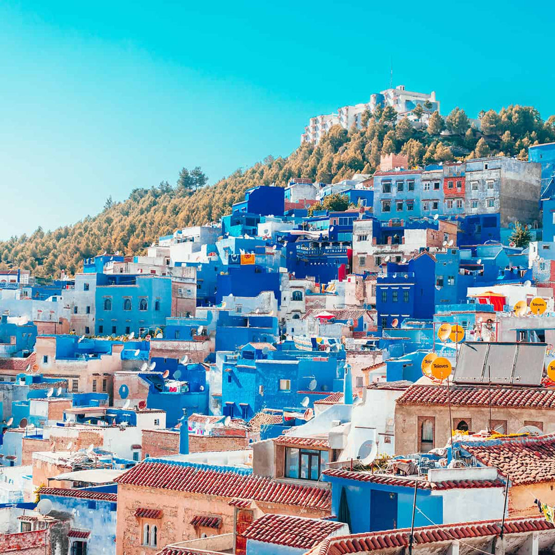 A vibrant view of the blue-painted buildings in Chefchaouen, Morocco, against a clear blue sky.