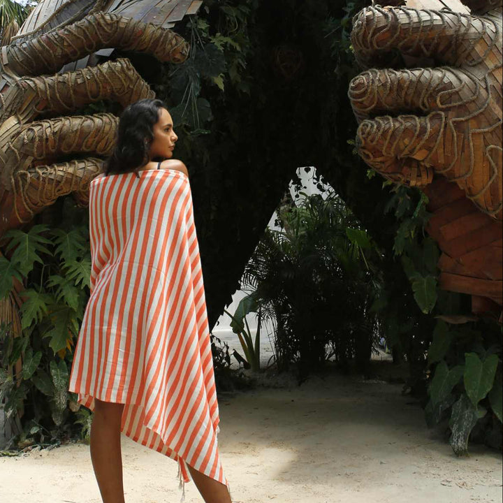 Woman in a striped dress standing in front of a large wooden sculpture of a turtle.