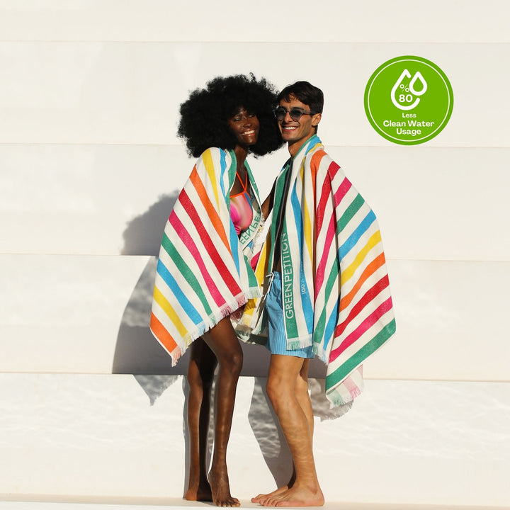 Two people wrapped in colorful striped  Green Petition 100% Recycled towel with a 'Clean Water Usage' logo in the corner.