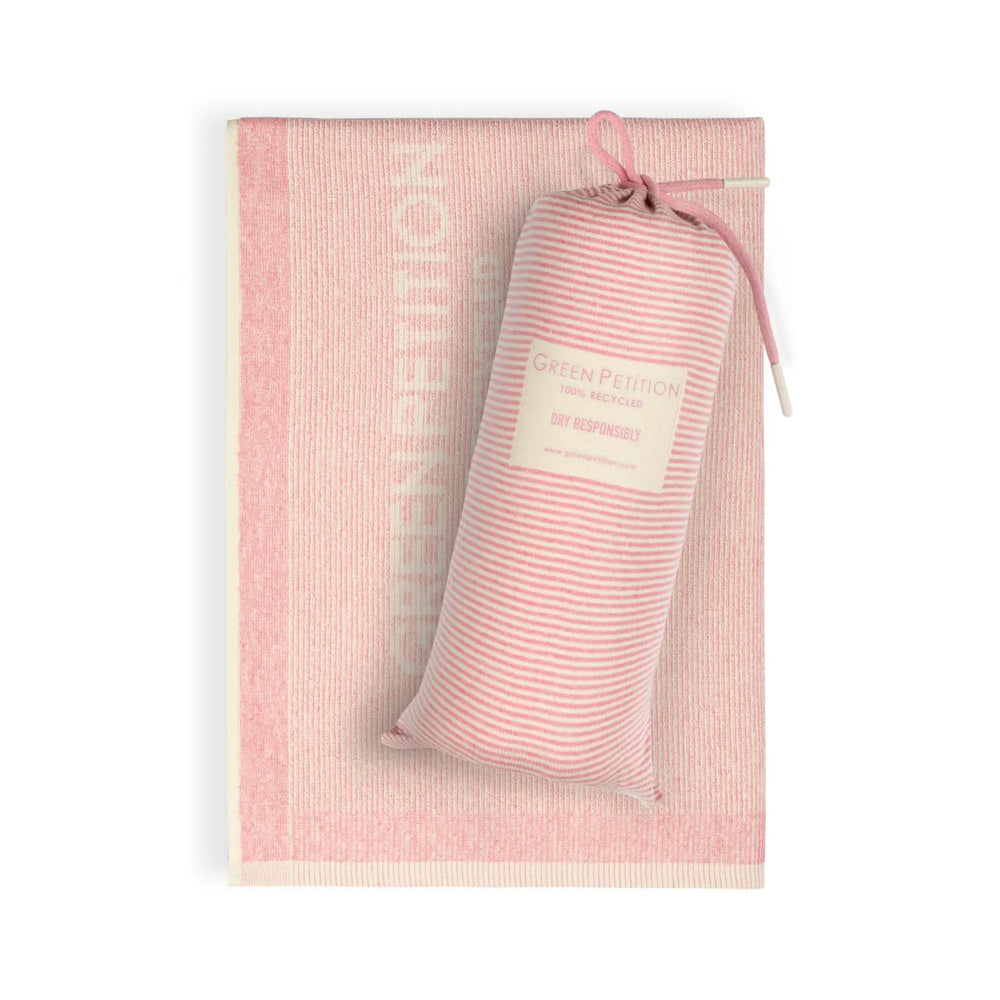 The pink-striped, folded Green Petition Calm Candy beach towel comes with its own mesh carrying bag. The bag is printed with the Green Petition brand name and the words "DRY RESPONSIBLY".