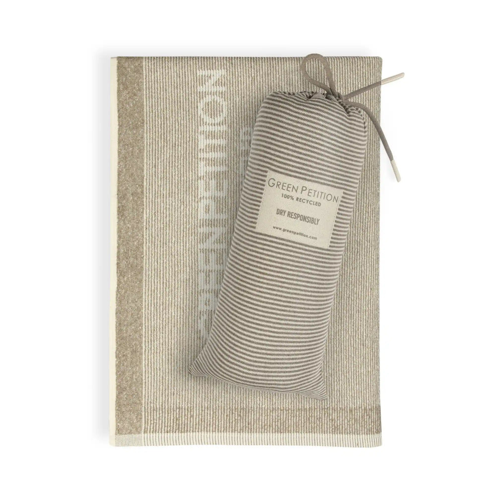 The Green Petition CALM clay towel is shown in a folded top view. Some letters of the brand name are visible. The original knitted carrying bag, branded "Green Petition", is also visible on the towel.