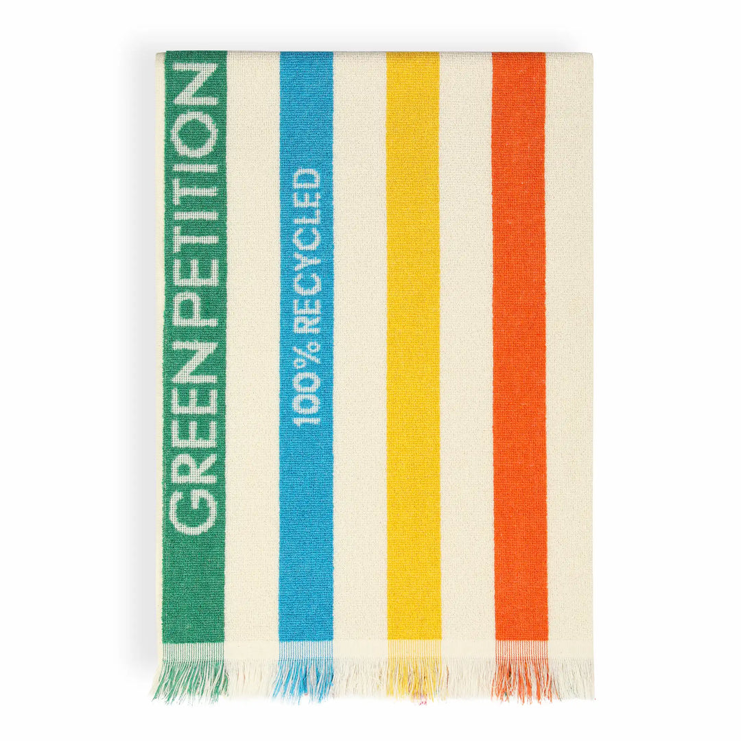 A striped woven textile with fringe at the bottom, featuring vertical bands in green, blue, yellow, and orange on an off-white base. The green band reads &