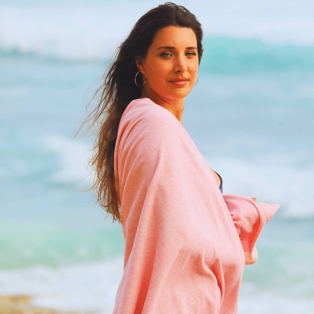 Woman in a Pink striped Green Petition Calm Candy beach towel standing on a beach with ocean in the background